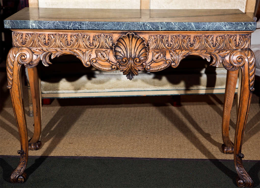 An English lime wood console carved with a central shell and acanthus motif and surmounted by a marble top.