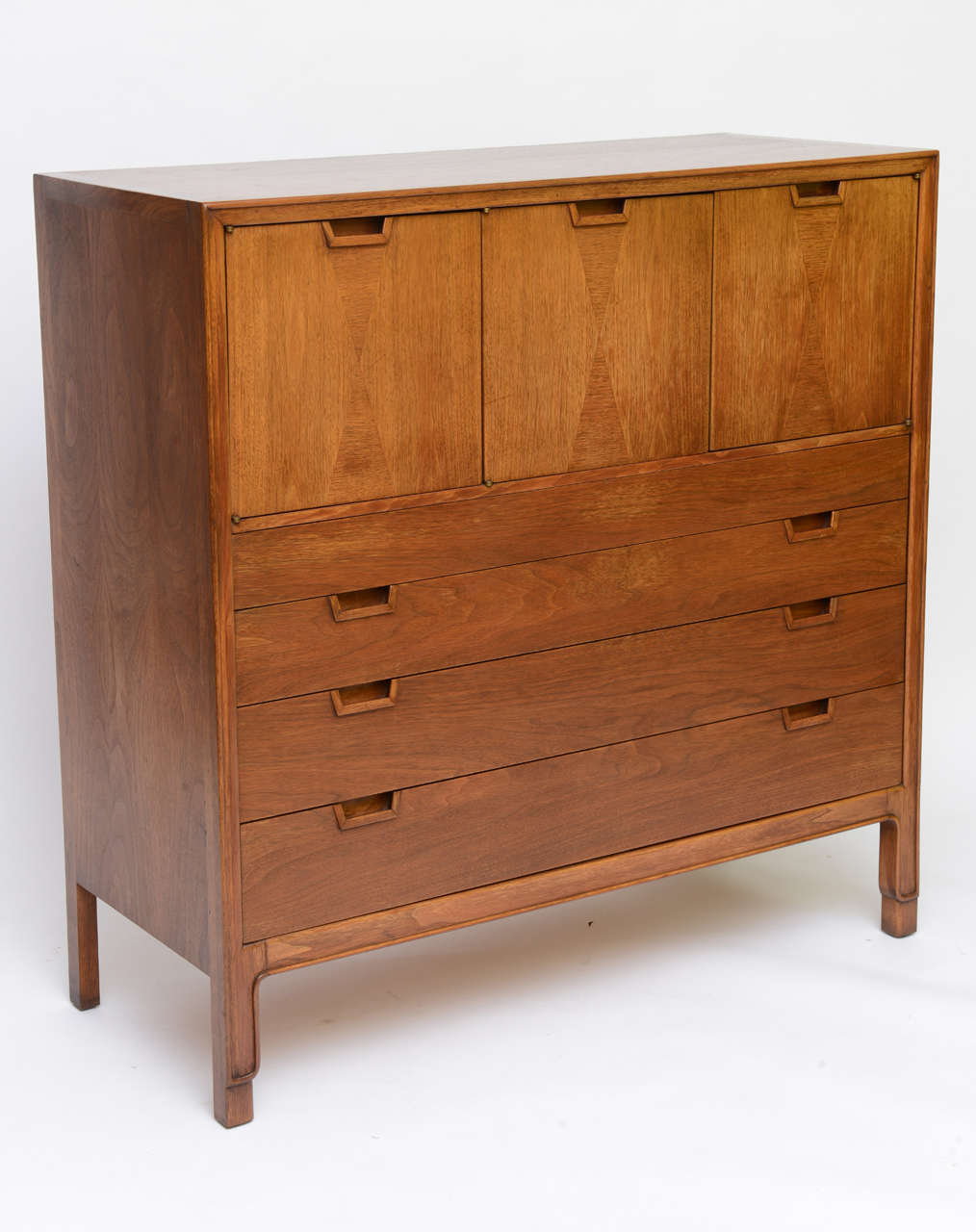 SOLD  John Stuart Janus Collection gentleman's chest of drawers or dresser in beautiful walnut. A modern form providing abundant storage with three top doors opening to shelved compartments above four  drawers. Harlequin inspired inlays on the doors