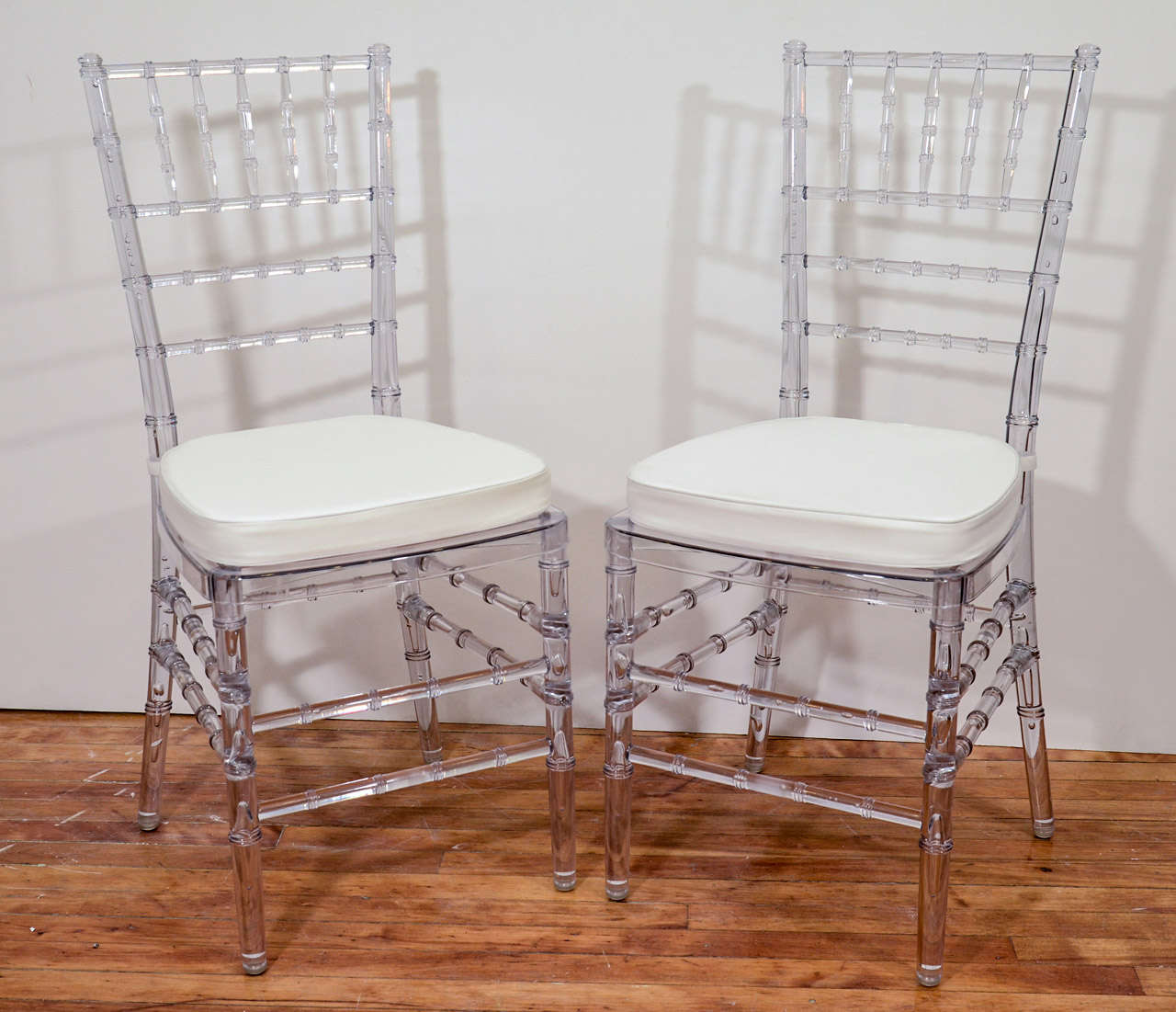 A vintage set of eight dining chairs with faux bamboo clear acrylic frames and white, removable seat cushions..