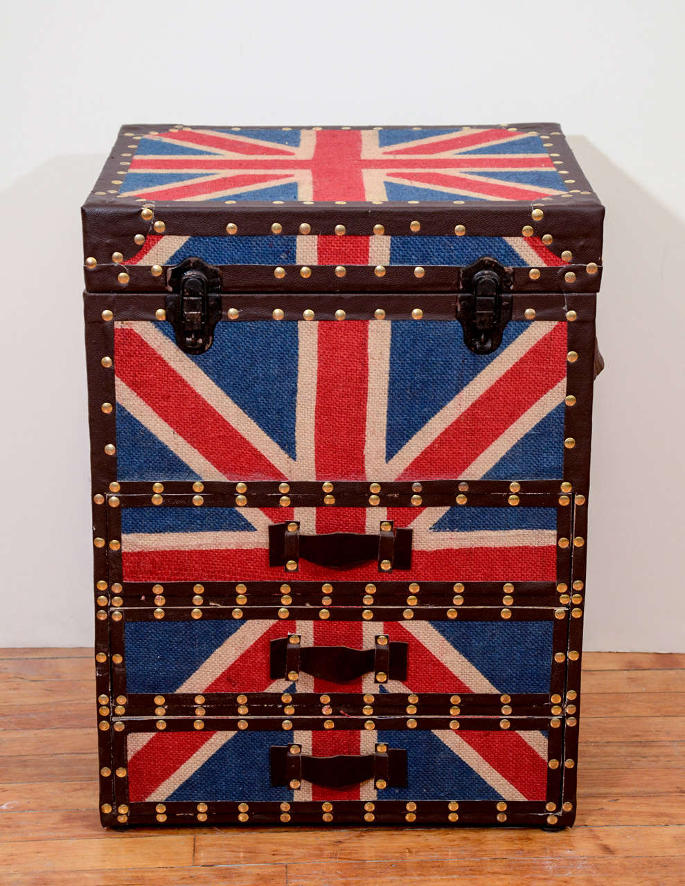 A vintage pair of Union Jack nightstands with three lined drawers, flip top upper storage and leather drawer pulls and trim. It is adorned with brass nail head detailing.