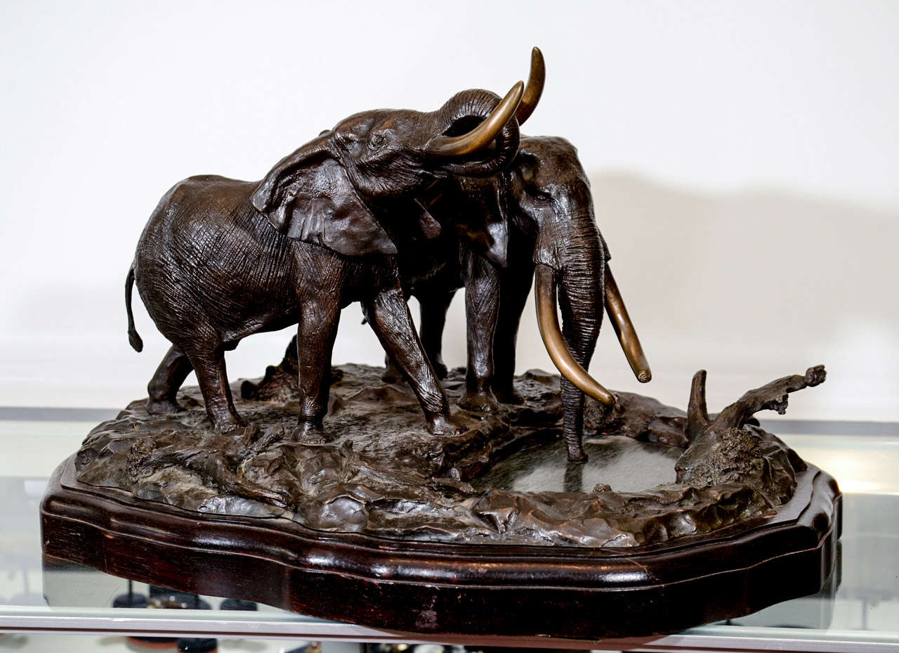 A vintage sculpture in bronze depicting two elephants in a landscape. The piece sits on a wood base. It is signed Robert Glen, 1976, 4/10.