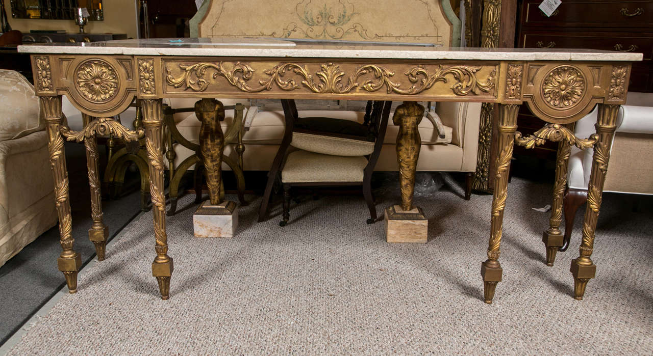 A finely gilt decorated marble top console table in the Louis XVI style. Carved and tapering legs having vine and leaf design supporting a carved frieze with garlands swags. The whole beneath a white marble top.