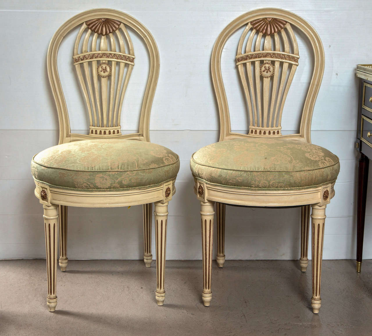 A fine set of ten dining chairs by Maison Jansen. Each having a gilt gold and off white paint decorated finish. The Louis XVI Style legs leading to a circular apron with gilt corner decorations and covered in a recent fabric. The back splats having
