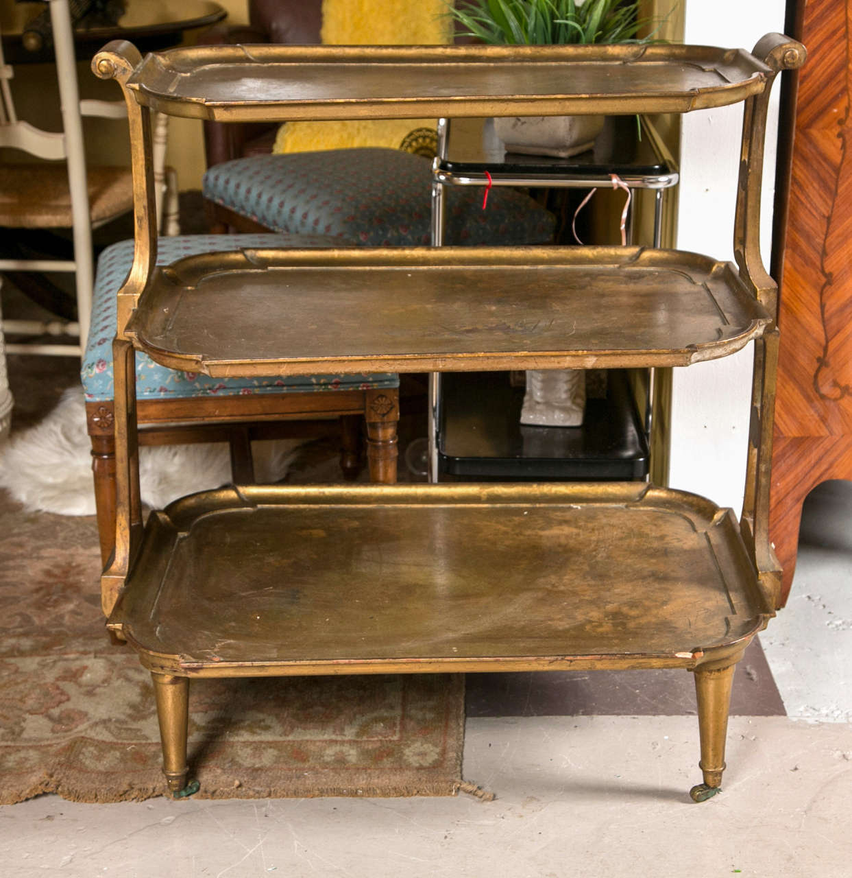 A Hollywood Regency Three Teir Serving Cart Tea Wagon. A fine wooden gilt gold decorated Serving Cart. The bronze casters on tapering Louis XVI style legs leading to a group of three shelves supported by flowing curved sides adorning handles. The