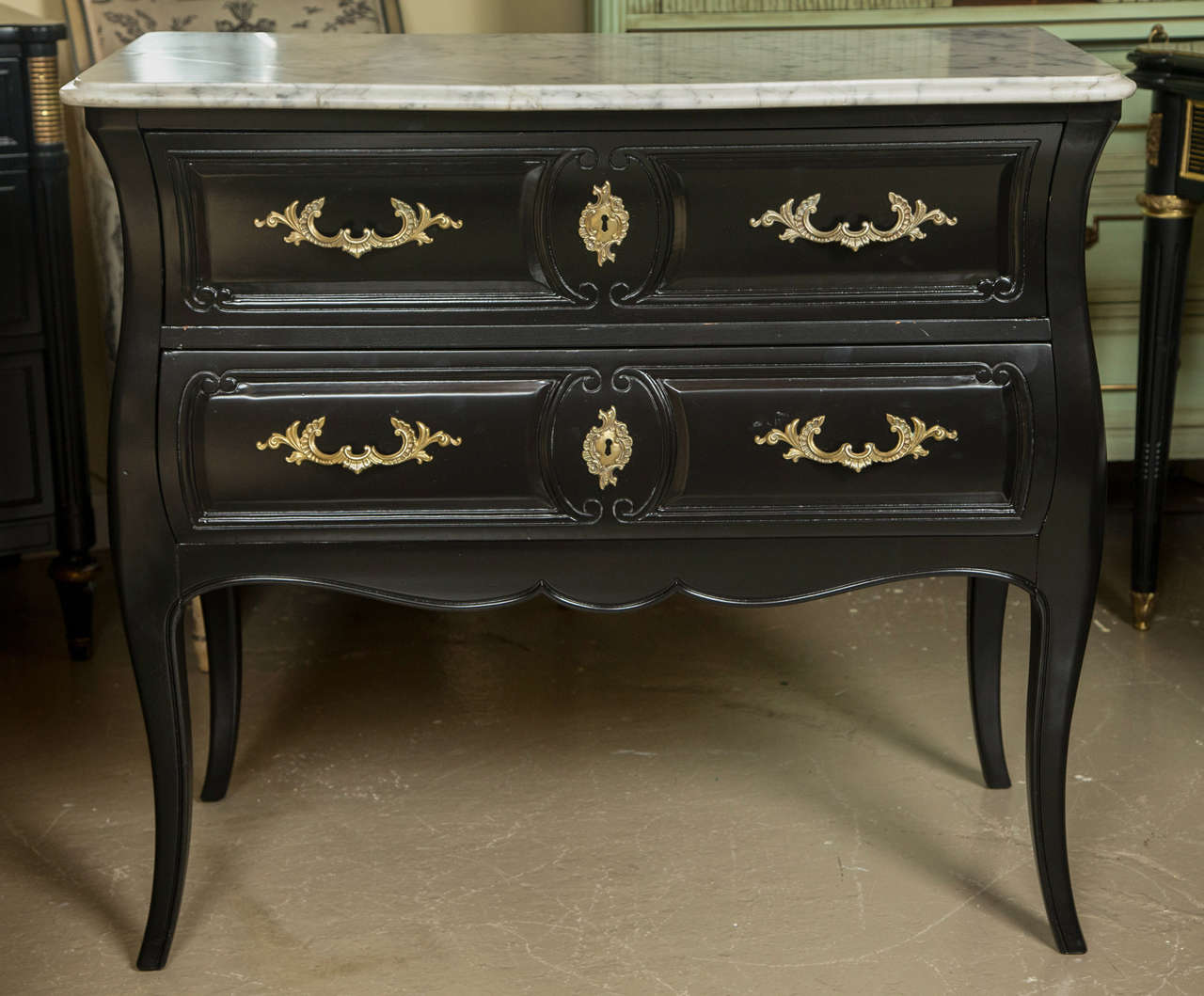 A fine ebonized and marble-top pair of commodes or nightstands by Maison Jansen. This rare and fine pair of double drawer bombe marble top commodes each having a Louis XV style leg supporting an upper case of bombe form. The whole leading to a white