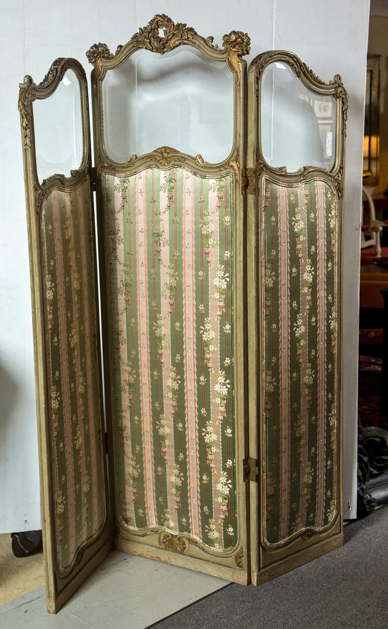 A fine French Painted and Gilt Decorated Folding Screen or Room Divider. This late 19 century screen is finely carved and detailed. The backs covered in Linen with silk green and beige upholstered fronts. The overall frame with rose and vine