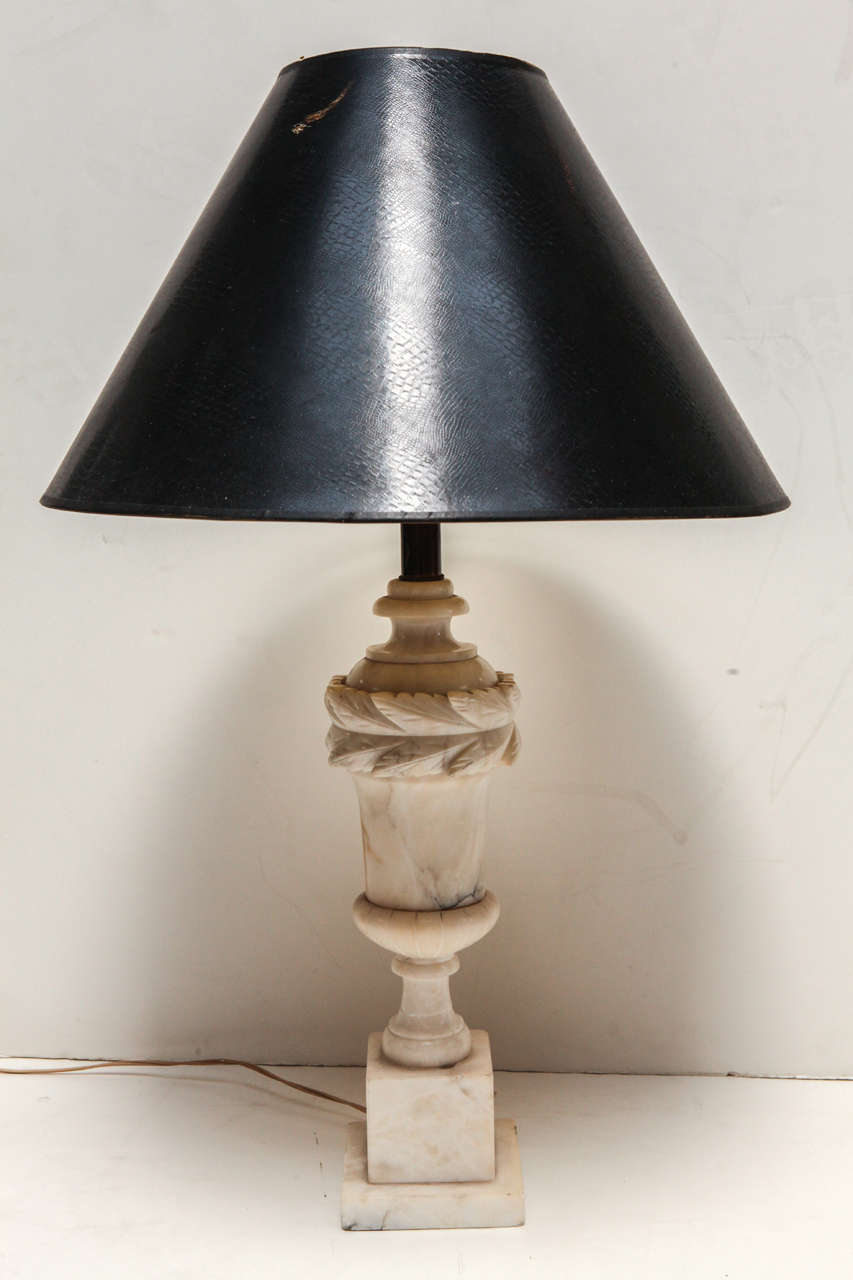Alabaster table lamp with detailed etching throughout and leaf detailing at top.