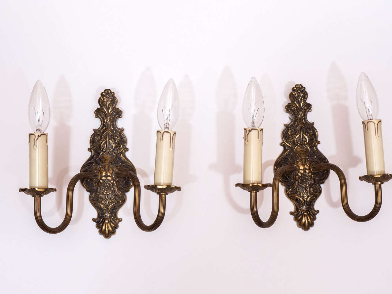 Heavy molded brass with a deep antique patina, these sconces evoke nineteenth century interiors, though they date from the 1920's.  Designed for electricity and bearing stylized, rather than classical motifs, these sconces are at home in any