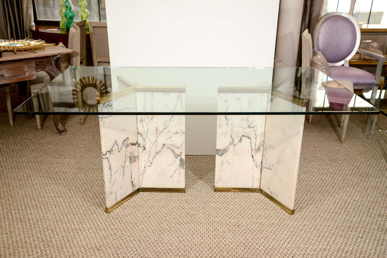 A fabulous dining table with a glass top on two marble and brass tripod pedestals. The pedestals could also be used to support two round glass table tops. The pedestal bases are Ca. 1970; the glass top is new. 