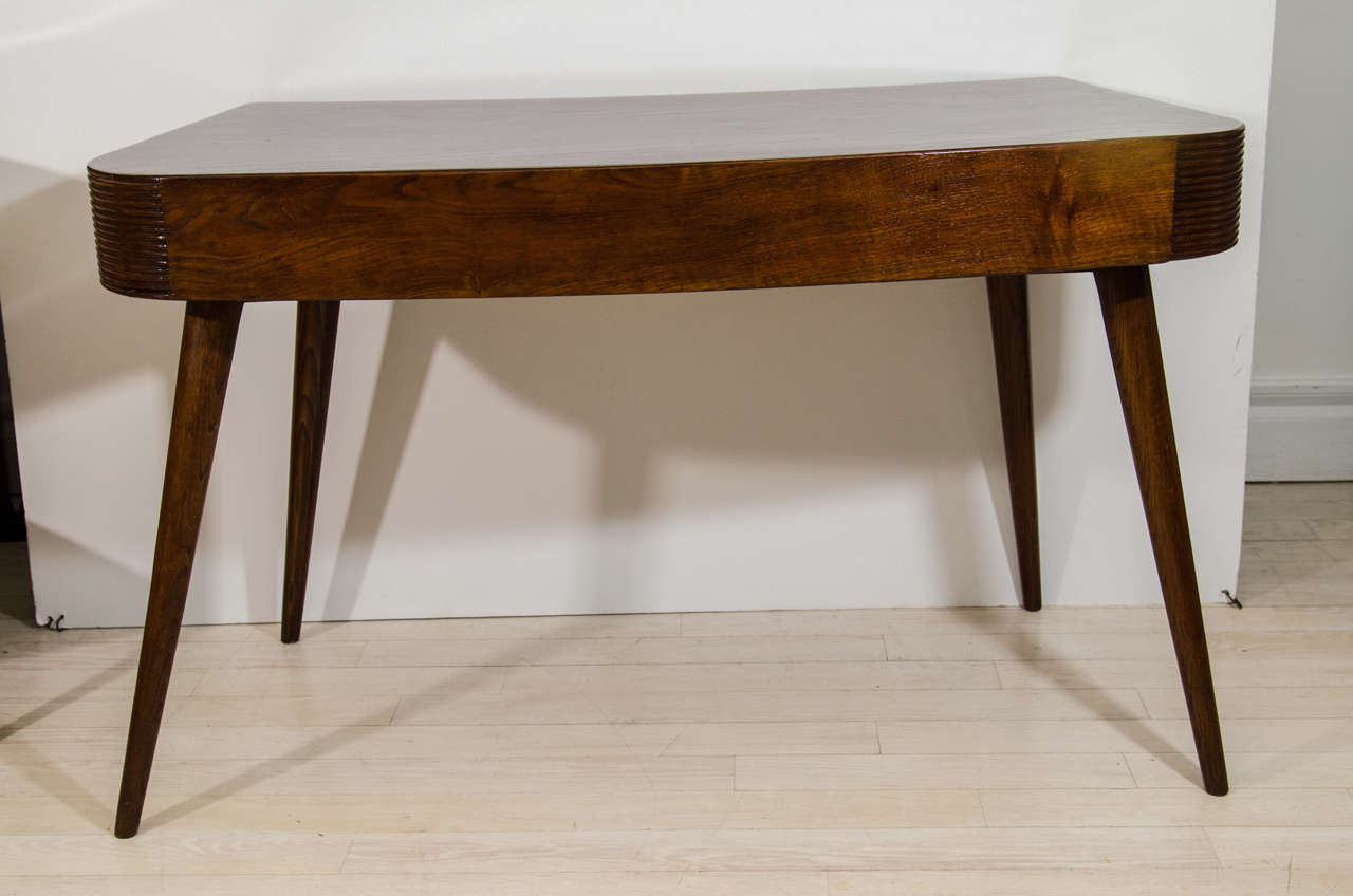 Two drawer shaped oak desk with reeded frieze over circular tapering legs