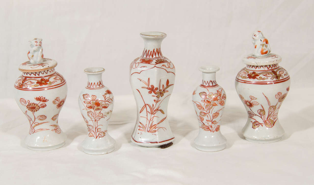 A rare miniature five piece porcelain garniture decorated  in iron red with garden flowers and bamboo. Comprising two covered vases with finials modeled as traditional 
shi shi lion dogs, a pair of smaller open vases, and a single tall open vase.
