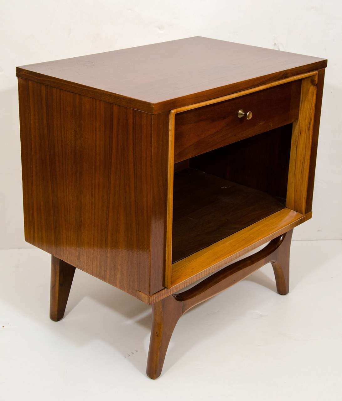 A pretty cube, crafted of walnut and birch and resting on a curved walnut frame. The cabinet has a single drawer, and large open compartment for books or periodicals. Perfect companion to any couch or bed; made to rest a beverage or book.