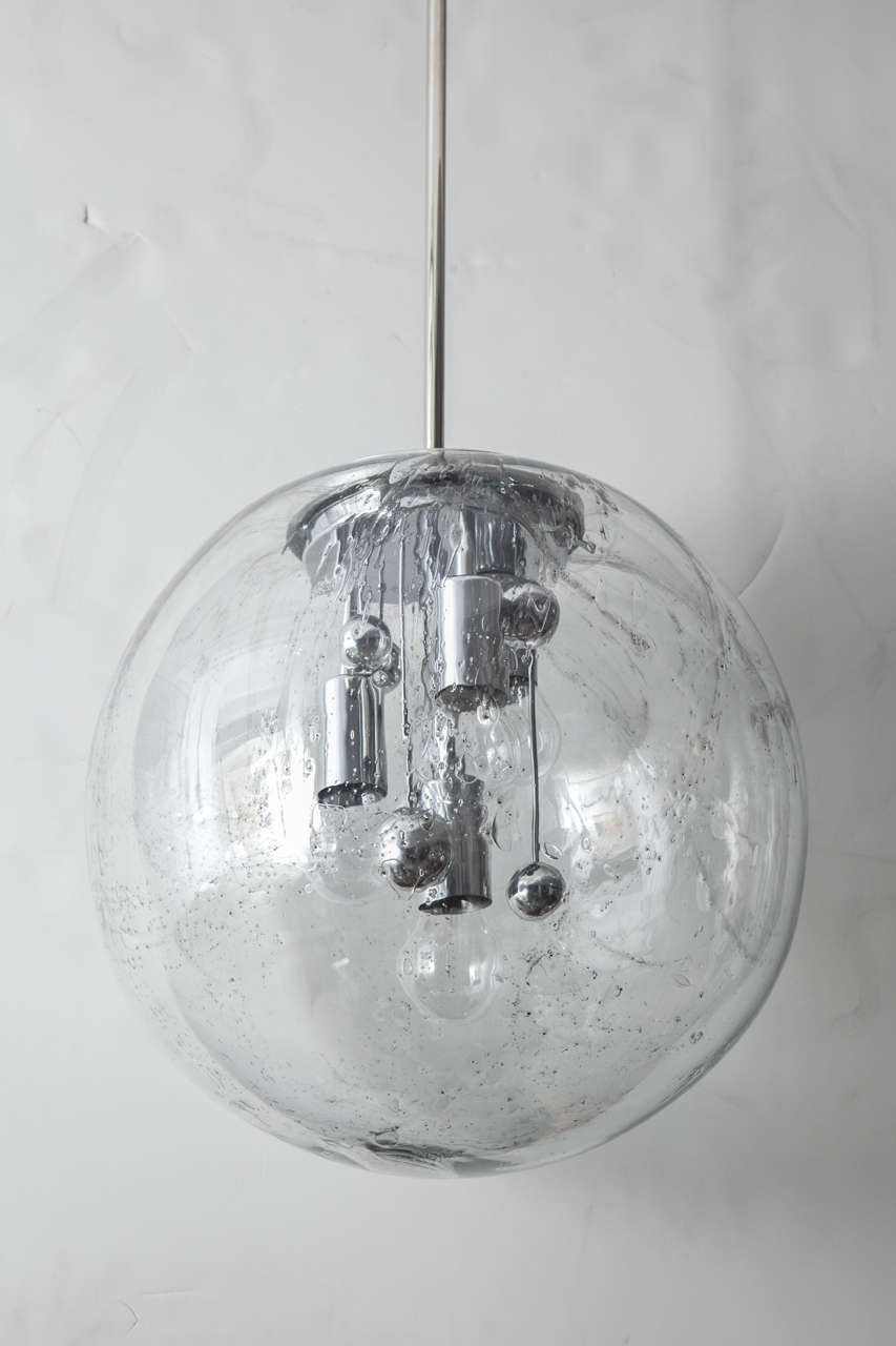 Fantastic extra large glass globe with bubble inclusions and a slight grey varigated glass vein. Pendants feature 4 light sources and suspended chrome spheres. Designed by Doria, Germany.