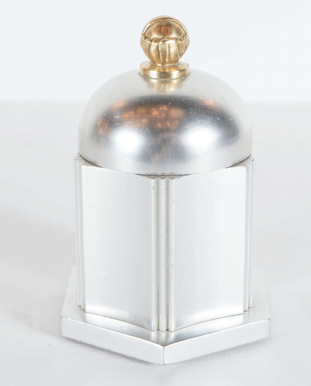 This Art Deco box features an octagon shape in polished aluminum with with a domed top with a brass finial. It bears the signature Kensington on the bottom. A great example of the Machine ages influence on Art Deco in America.