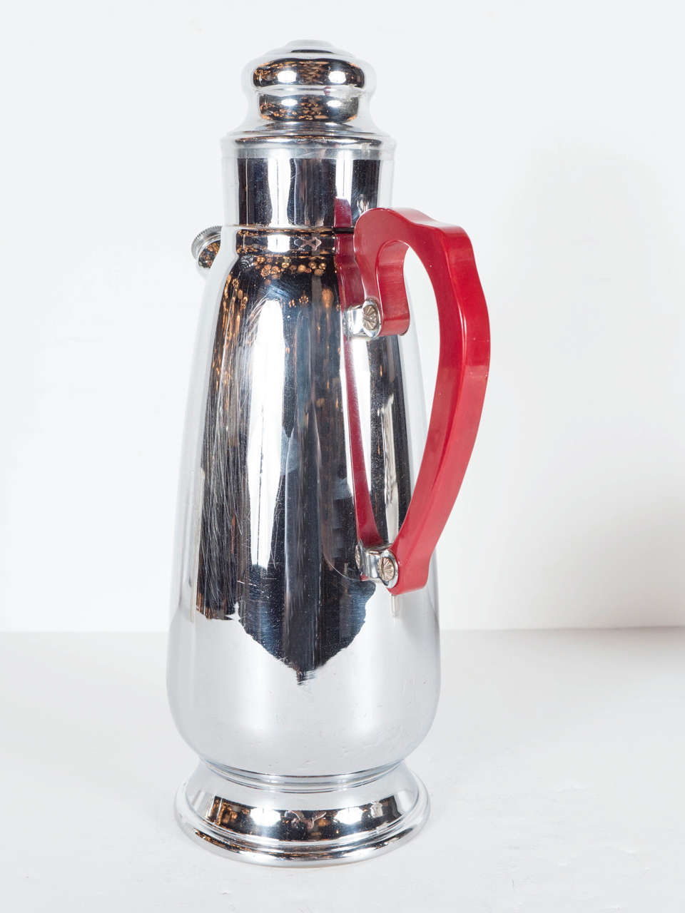 This gorgeous cocktail shaker is chrome with a red bakelite handle handle and epitomizes the Machine Ages influence on Art Deco in America.