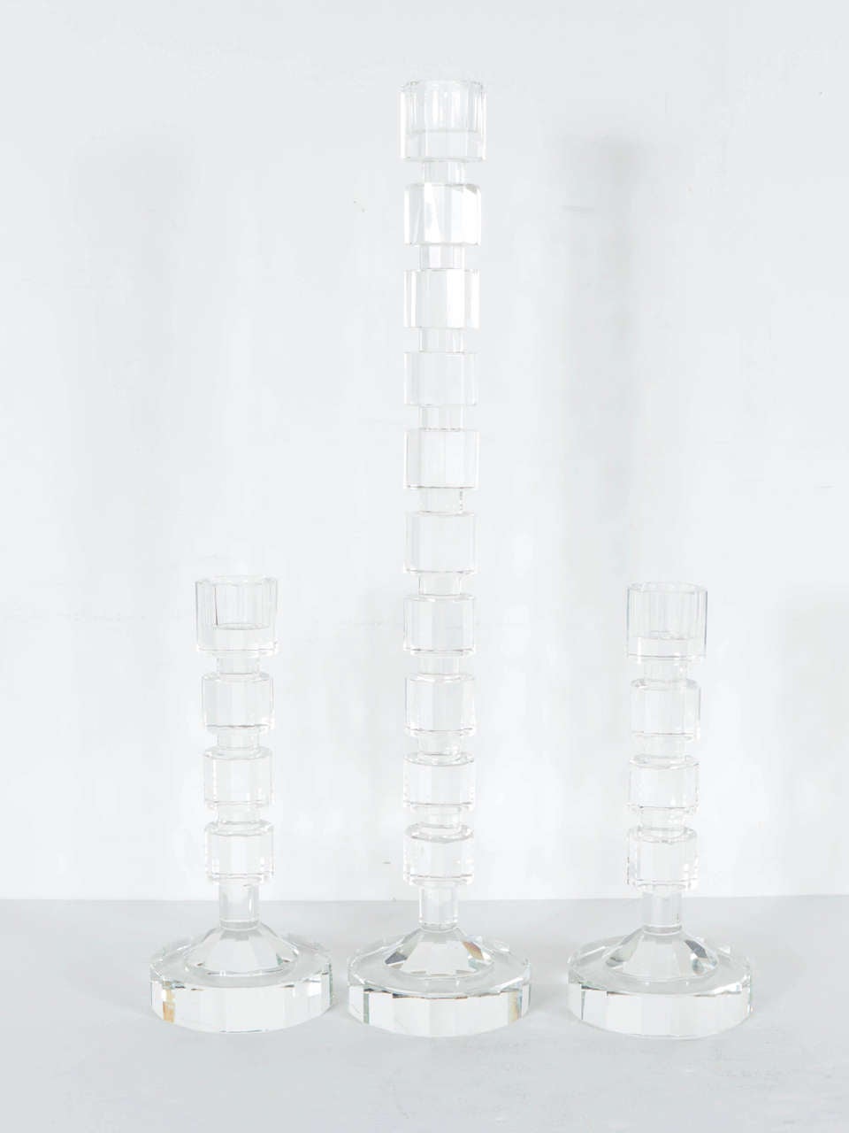 These set of three candleholders feature  a geometric Art Deco style in cut crystal . They are columnar if form with cut crystal cubist design.Thye bear the name Shannon on the bottom.
