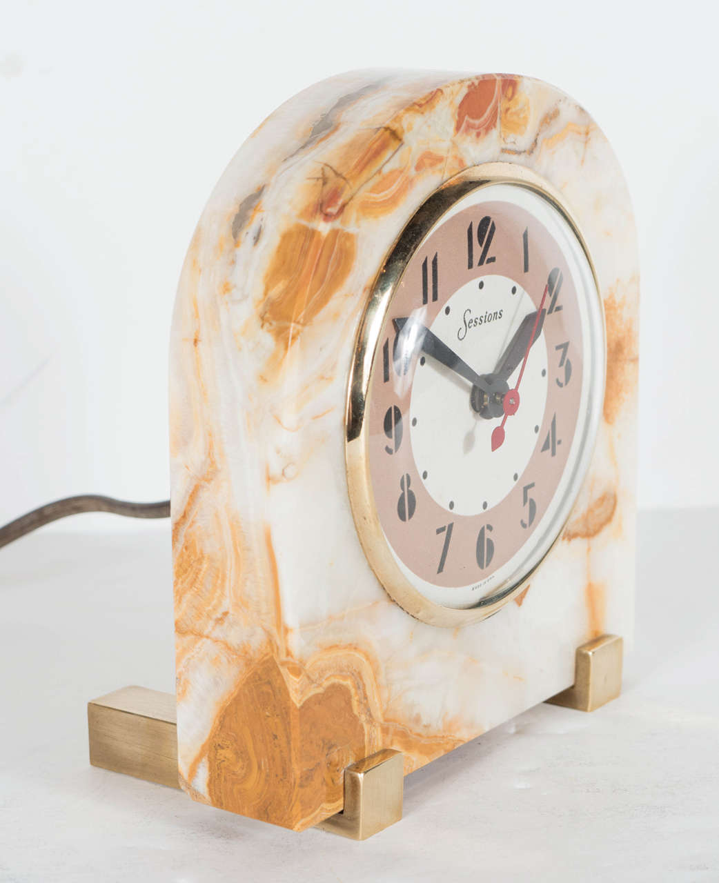 This outstanding Art Deco electric clock by Sessions features an exotic onyx surround with solid brass banded supports, a circular face with glass dome cover and brass trim and numeric numbers to indicate the hour. In perfect working order.