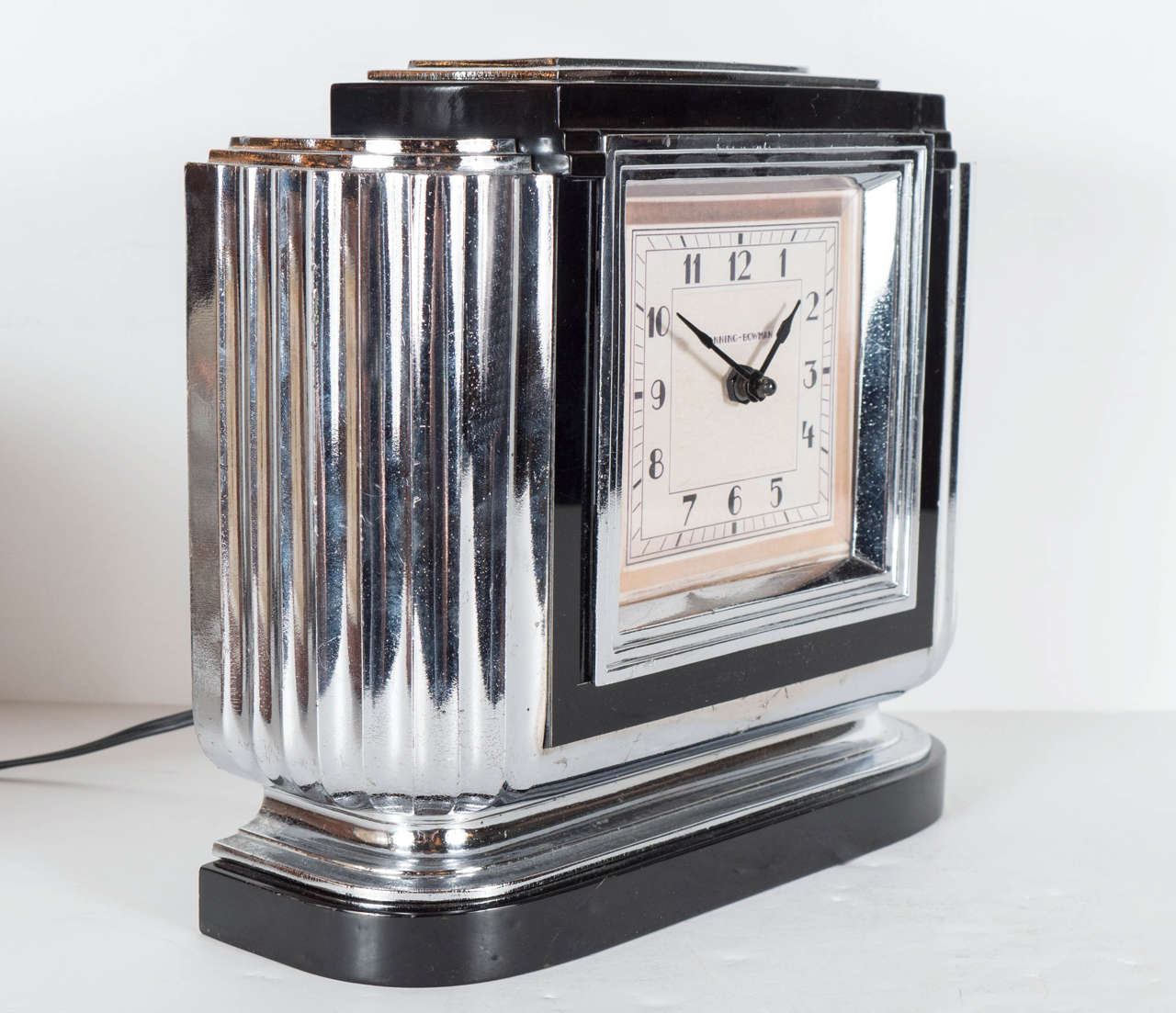 This exceptional skyscraper style electric mantel clock is by Manning Bowman. It features a skyscraper stepped style design in chrome with fluted detailing on the side, and black enamel accents. It has a square face, streamlined design, and can be