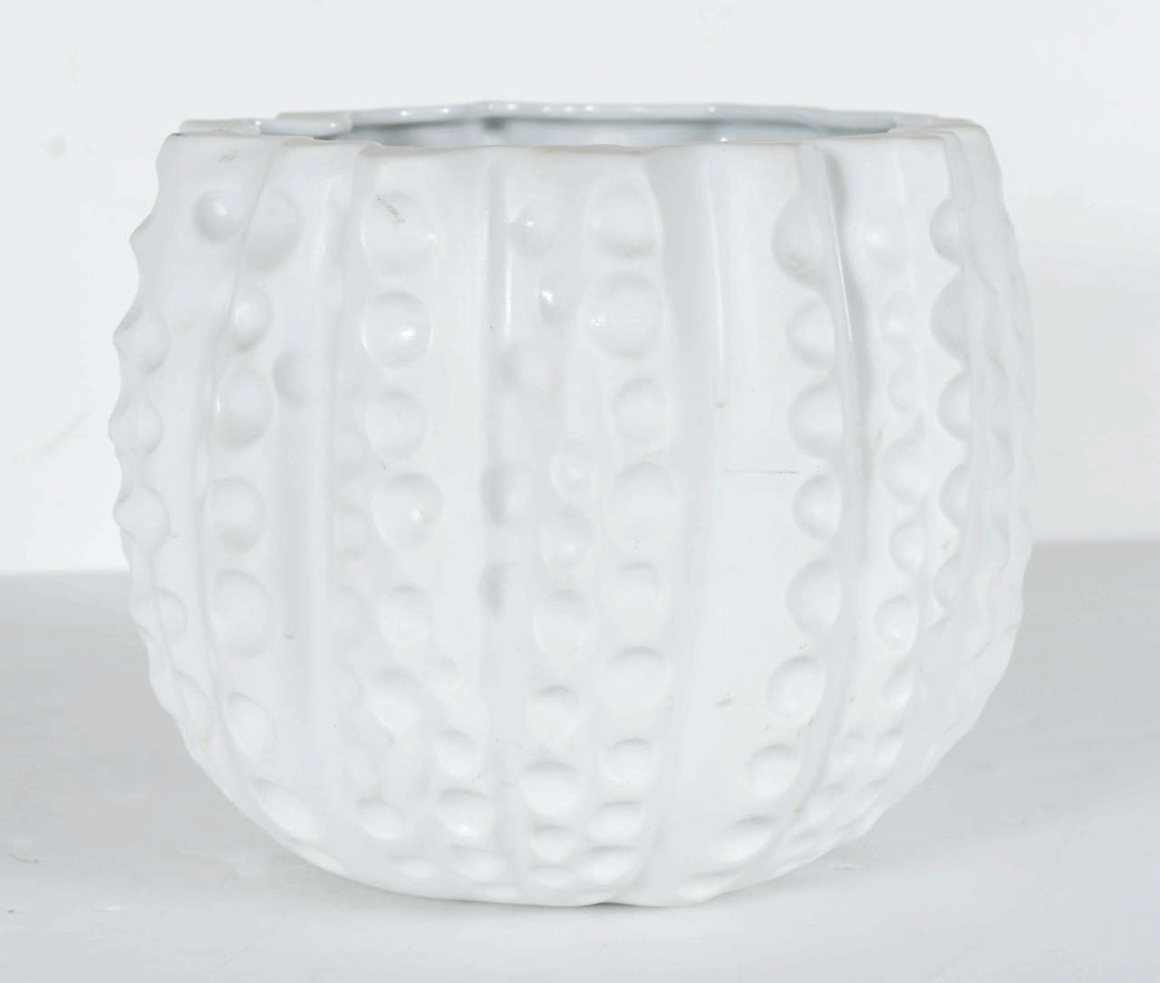 This gorgeous modernist Japanese style Jardeniere is quite the accent piece. It is fine kiln dried porcelean in a matte  finish.The intricate detail on the curvature and the Urchin style circular holes on the outside of the ceramic porcelain base