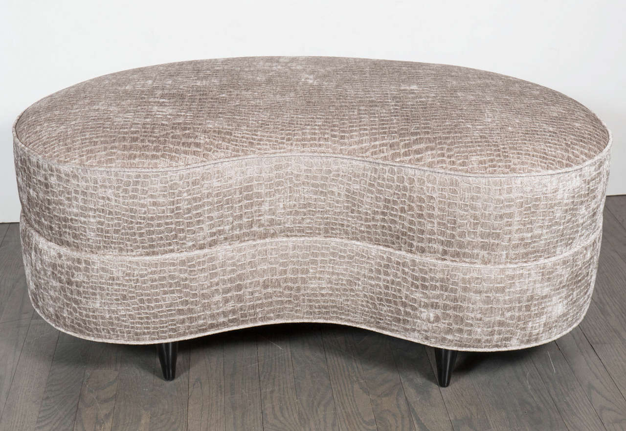 This spectacular Mid-Century Modernist organic shaped ottoman is a beautiful piece. It features smoked gauffraged crocodile velvet upholstery and ebonized walnut tapered legs. The detail and shape of this ottoman make quite a statement, and would