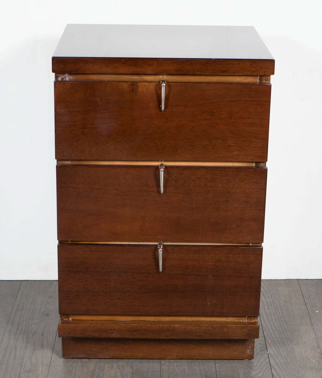 This stunning pair of Mid-Century Modernist walnut nightstands / side tables are beautiful in it's shape and design. Crafted in a beautiful rich walnut with stylized nickel geometric pulls, it's simplicity is sure to make a statement to any