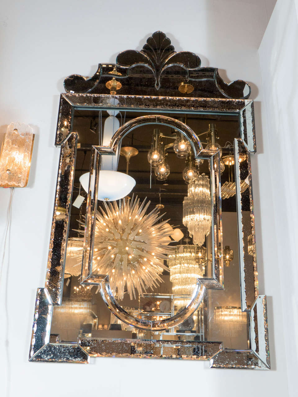 This stunning smoked antique venetian style mirror is gorgeous. It features a chain bevel detailing and a cartouche on top adding a beautiful asymmetrical shape to it's design.Its borders are all smoked antique mirror and all hand beveled.