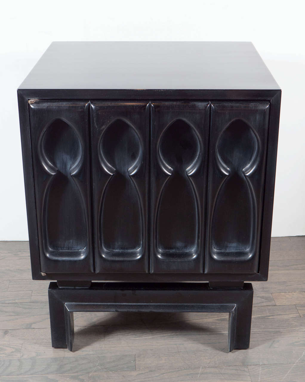 This ultra chic pair of Mid-Century Modernist sculptural front end tables or nightstands are very sophisticated. They feature a beautiful relief front of sculptural design in hand rubbed ebonized walnut. The door opens to reveal a cabinet with a