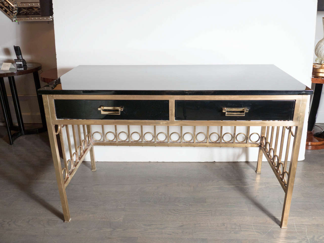 This exceptional Mid-Century Modernist desk features a strong geometric design, a brass frame with vertical bars spaced by a circle between each at the top and bottom. The desk top and drawers are ebonized walnut bordered in brass with lineal brass