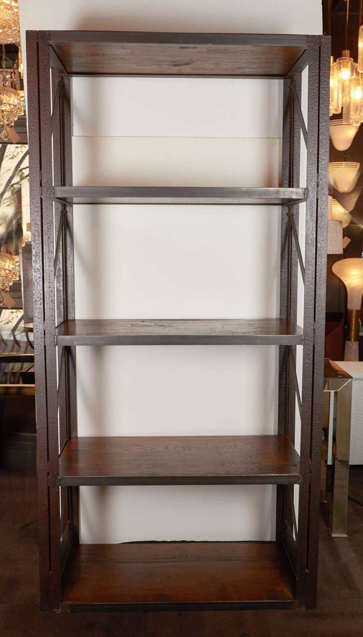 Outstanding Industrial bookcases fitted with reclaimed wood shelves. Grand-scale design comprised of heavy-set hand-forged steel frames with patinated rust coloring. The bookcases feature five shelves in heavy reclaimed walnut wood with a medium to