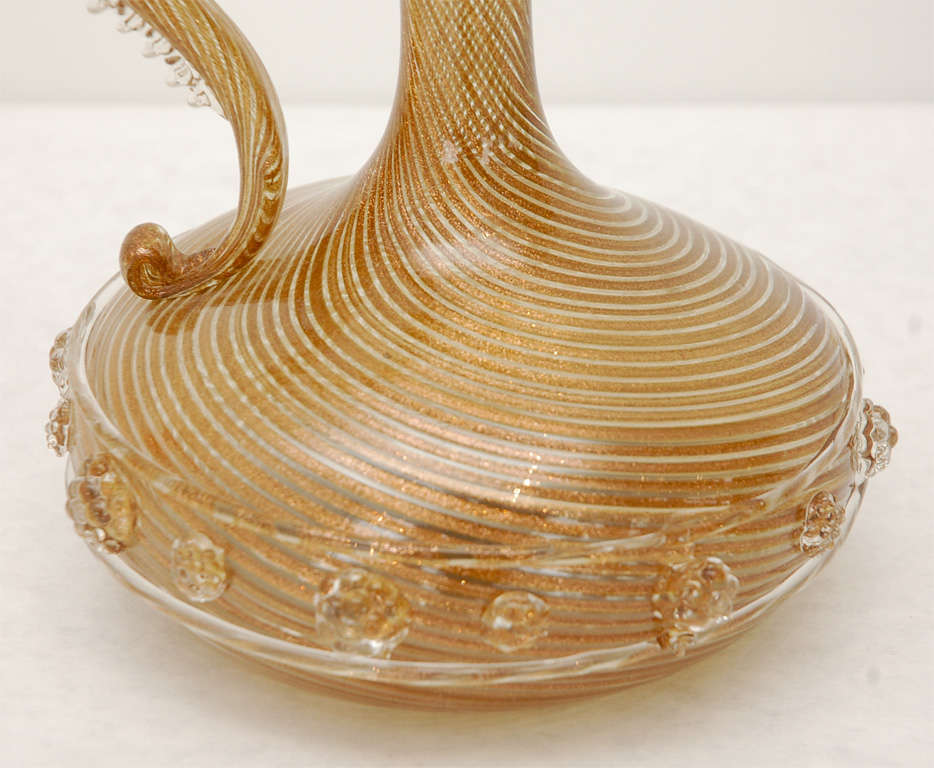 A sparkling Murano glass Ewer flecked featuring metallic copper and white glass threads with clear glass detailing along the handle and florets around the circumference.