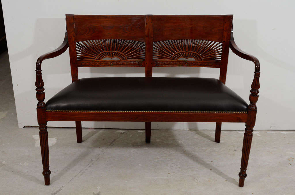 Early 19th century Colonial Sheraton bench very beautiful with sunrise carving backrest . Turning and reeded front legs, cylinder shape tapered arrow foot. Wide top rail, curved arm rests and is upholstered seat with black leather.