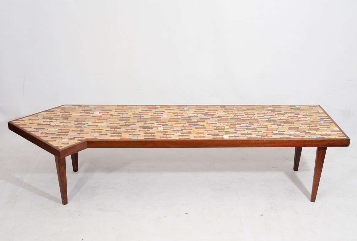 Handsome coffee table with an unusual, dynamic form designed by Hohenberg. The top is a nicely executed tile mosaic.