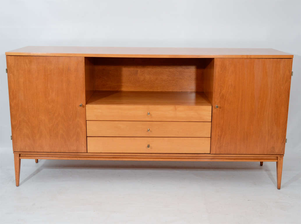 Handsome solid maple credenza or sideboard by Paul McCobb; designed for his Planner Group. Accented with brass pulls and exposed hinges. Nicely refinished, the design presents subtle contrast in tones and color of the maple. A versatile piece which