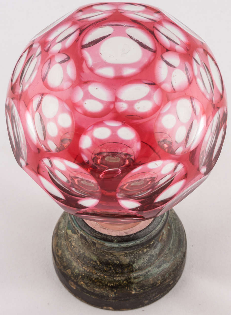 Une belle Boule d'Escalier du milieu du 19ème siècle en verre canneberge à facettes sur une monture en laiton patiné.