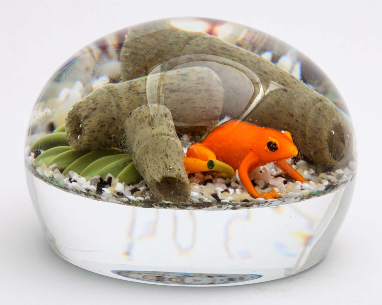 A Gordon Smith paperweight with an orange tree frog with bamboo and leaves on a rocky ground