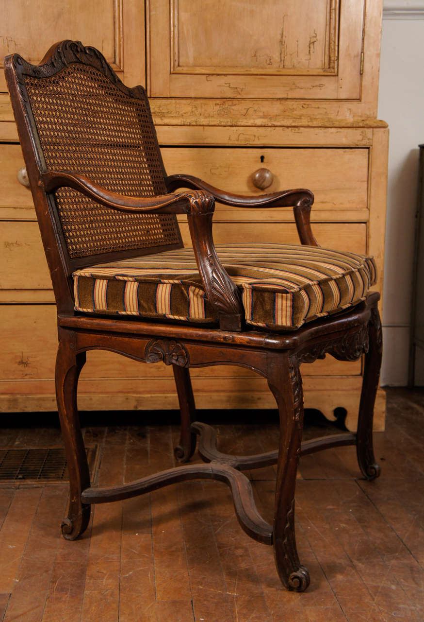 Regence late 18th century carved fauteuil with caned seat and velvet fitted cushion.