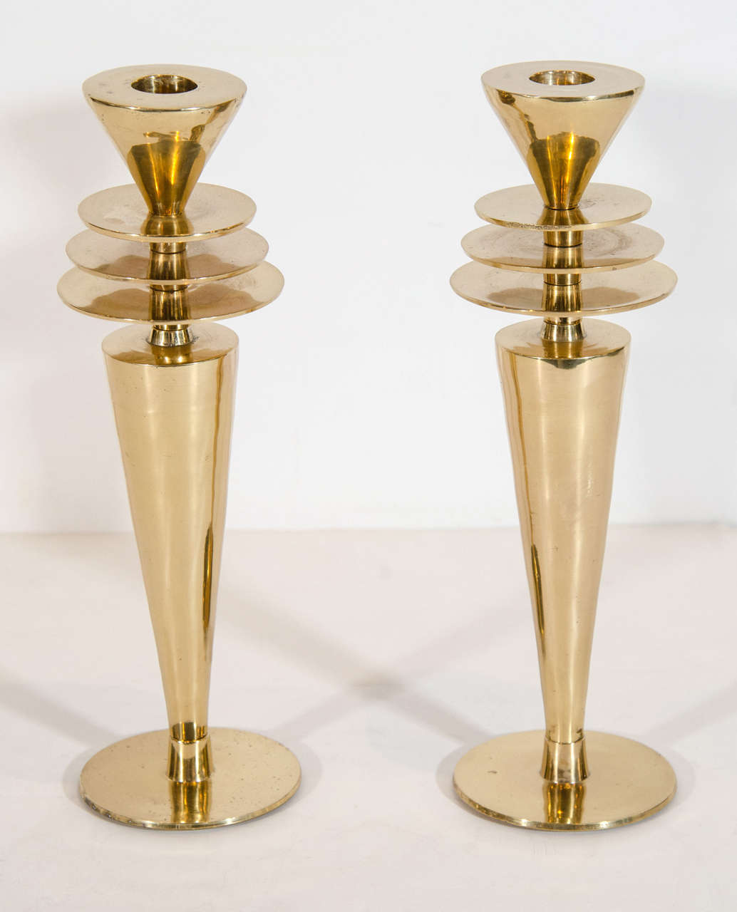 Pair of highly stylized Art Deco candlesticks with tapered stem design and Machine Age / Skyscraper inspired stepped tiered details, and circular base.