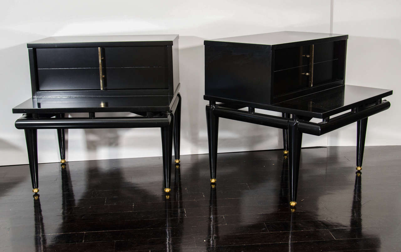 A pair of black lacquer side tables with a large drawer having one single handle. The legs have a brass foot as a nice finish.
Freshly lacquered.