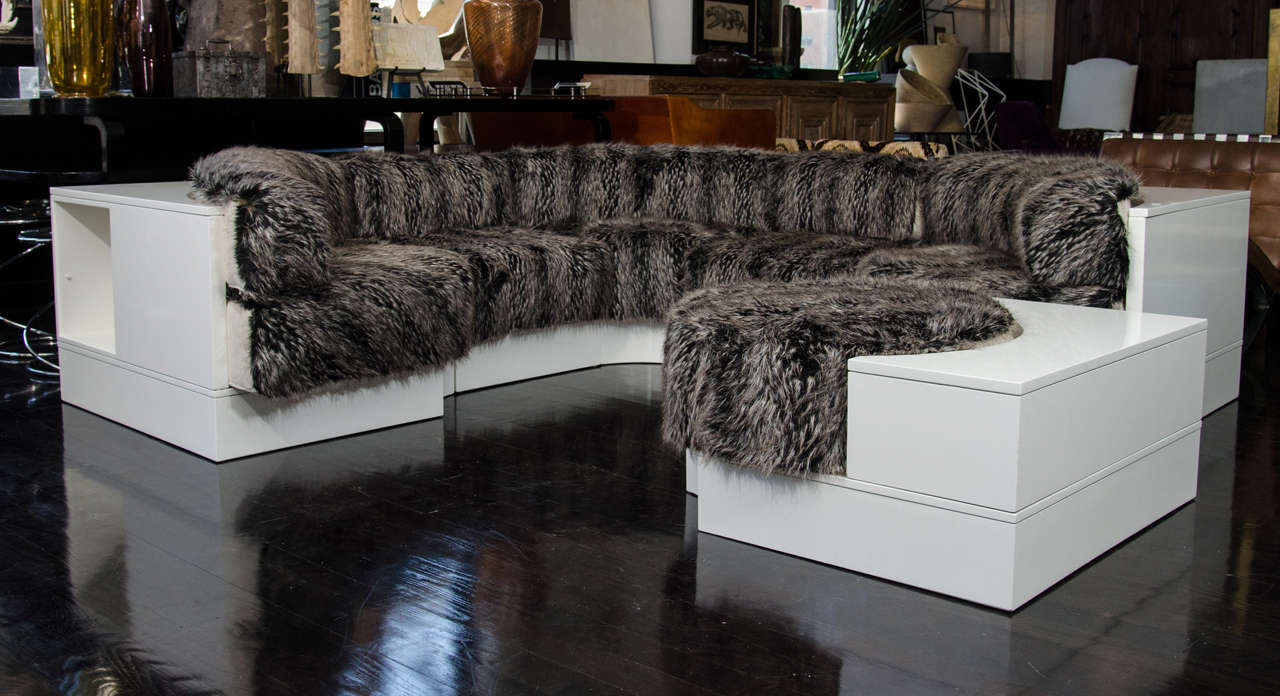 A super hip sectional sofa 
The exterior frame is lacquered in a high gloss white with a combination of linen and faux fox fur.
The corner sections have cubbies for books, the round ottoman creates extra seating and leg room. Great for a media