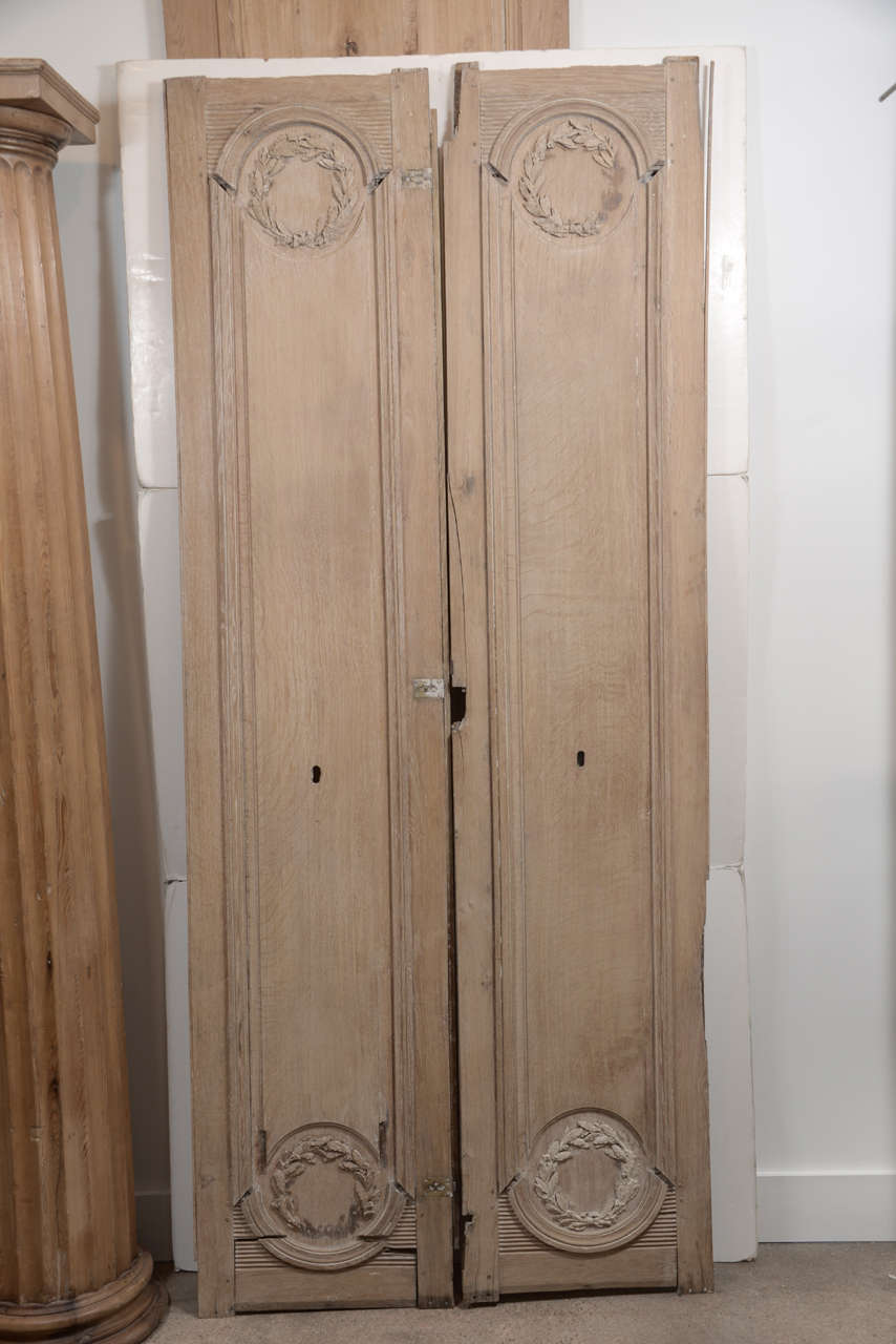 Pair of 18th century French panels from doors with traces of original paint and carved wreath detail.