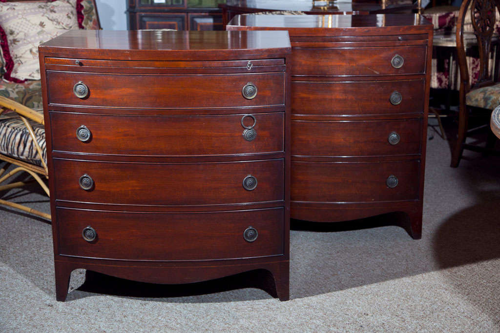 Fine pair of custom quality bachelor chests - commodes. Each Sheridan style chest having four graduating bow front drawers leading to a pull out leather top serving / writing tray. Produced by the Landstrom Furniture company.