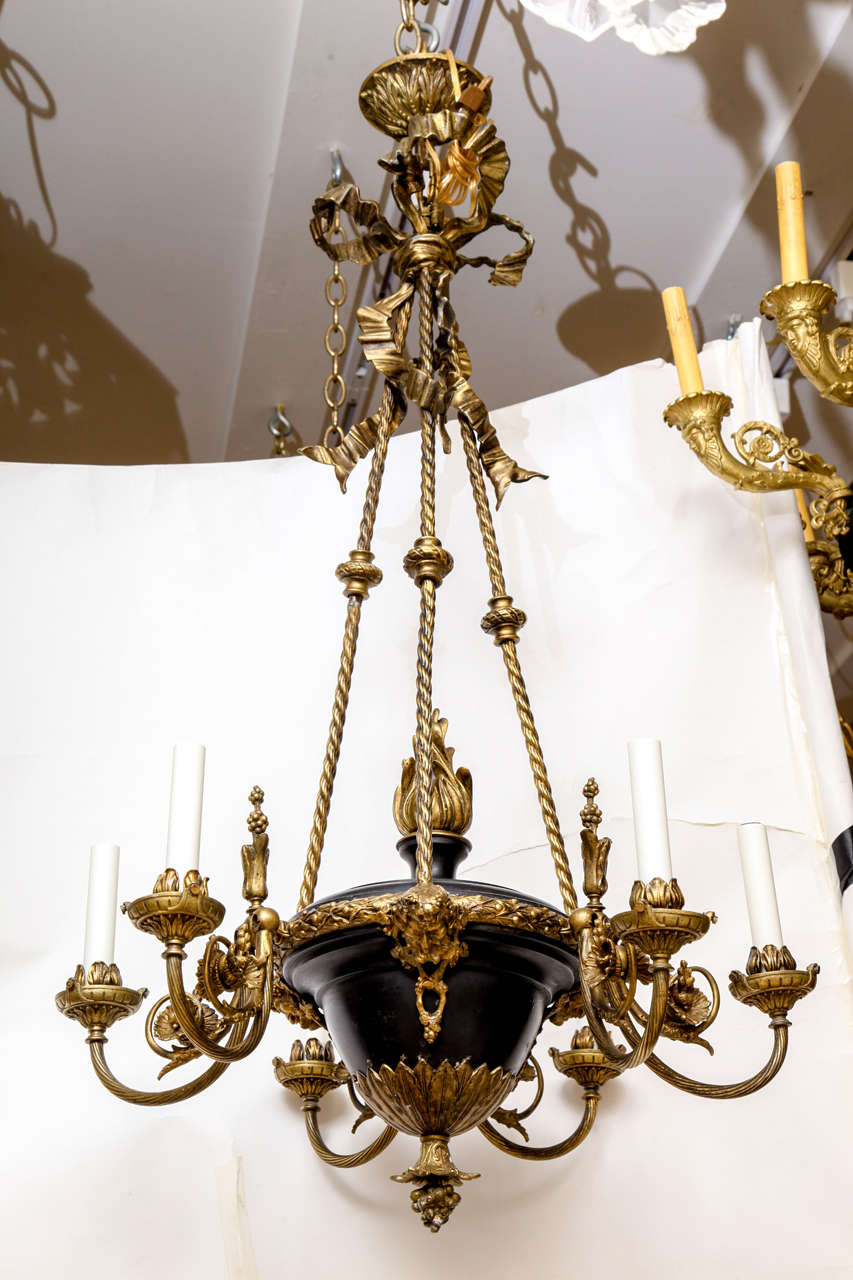 A six light French Empire tole chandelier with vase shaped body suspended from bronze trompe l’oeil rope and tassel surmounted by bow the center with flame shaped finial.   