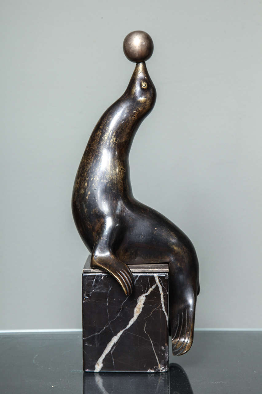 Jan and Joël Martel (1896-1966) brown patinated and silvered bronze representing a sea lion playing with a ball and resting on a marble base, circa 1930. Signed "J.J.Martel." H: 13 1/3 in.