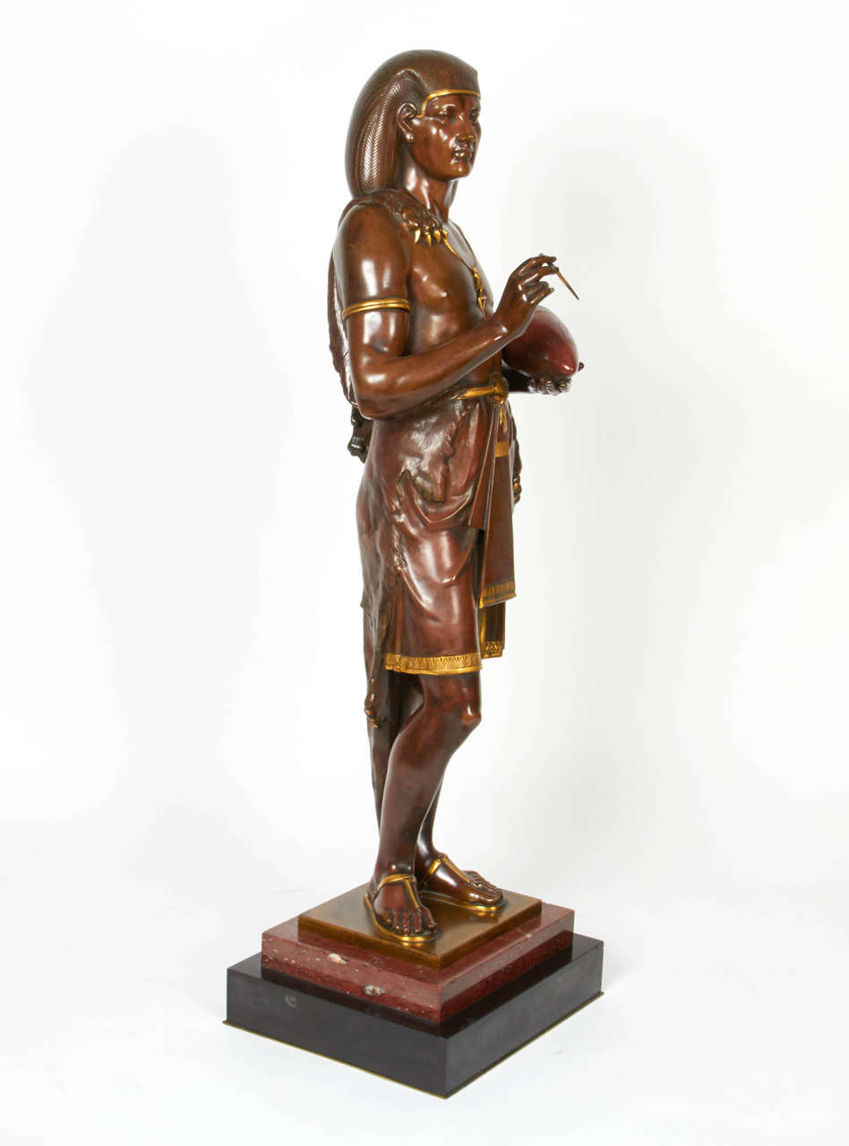 A very large bronze figure of an Egyptian Scribe by Emile Louis Picault (French, 1833-1915), beautifully modeled and detailed with the finest quality with its original brown patina with gilt highlights and detail, and original rouge marble carrara