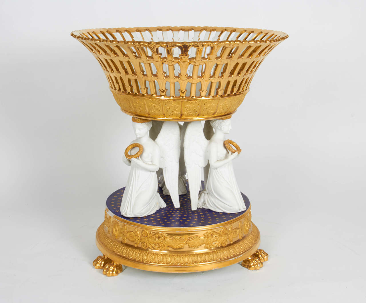 A magnificent and large Russian Empire porcelain gold ground and white bisque figural reticulated centrepiece. A large filigree basket supported by three addorsed kneeling winged female figures, beautifully hand chiselled and detailed, all seated on