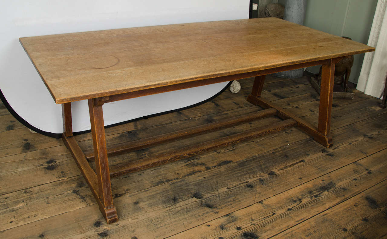 Dining table with planked top above tapering outplayed supports and trestle ends, united by a double stretcher, English, circa 1890.