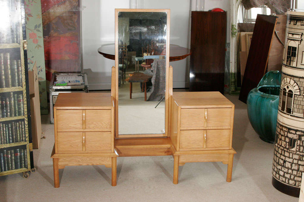 A Gordon Russell oak dressing table of twin pillar construction with a central platform and hinged mirror. Supported on chamfered legs.
The drawers with moulded vertical handles.
England, circa 1930.
