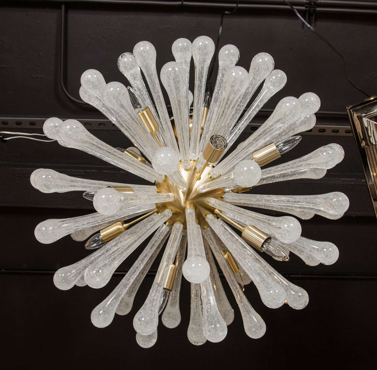 This dramatic glass sputnik chandelier was hand blown in Murano, Italy- the island off the coast of Venice renowned for centuries for its superlative glass production. It features an abundance of effervescent semi-translucent glass rods with