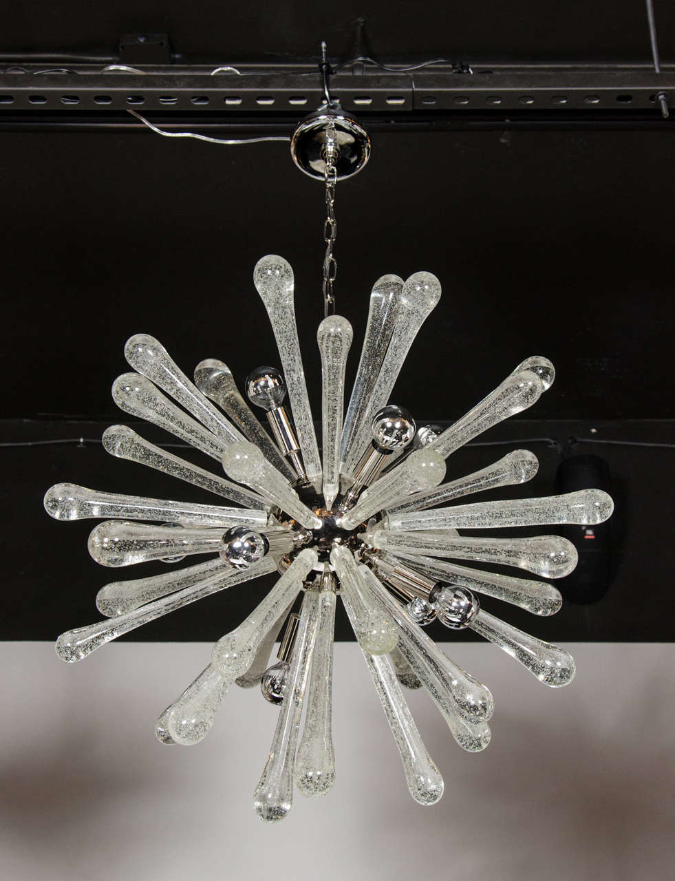 This stunning Murano glass Sputnik style chandelier was realized in Murano, Italy- the island off the coast of Venice renowned for centuries for its superlative glass production. It features an abundance tapered textured glass rods emanating from a