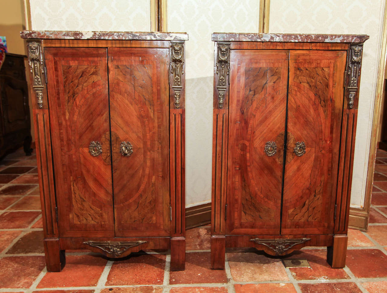 Pair of French Louis XVI corner cupboards or encoignures.

This is a pair of rare corner cupboards with the marquetry inlay with an oval band and arched imbricated panels flanked by line inlaid stiles.

Both cupboards have the original bronze